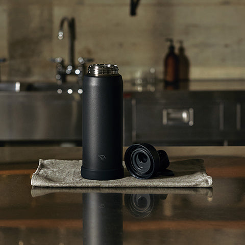 Black insulated bottle with a cap on a kitchen counter