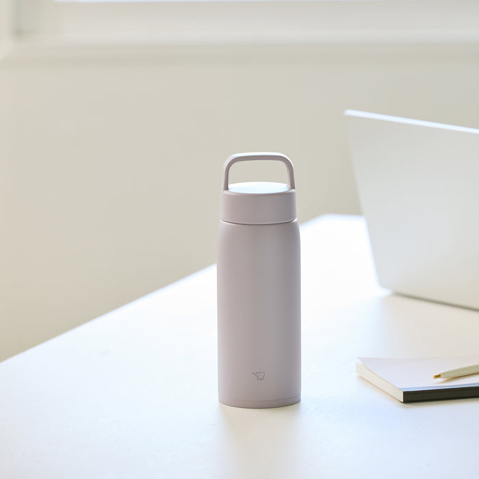 Bottle on a desk next to a laptop