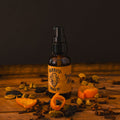 Mammoth Beard Co. Imperial Spice Beard Oil bottle surrounded by dried orange peel, clove, and cardamom on a rustic wooden surface, showcasing its warm, spiced autumn aroma.