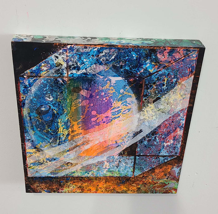 The artwork 'Galaxy Delivery' features vibrant cosmic swirls in deep blues, oranges, and purples, creating an abstract celestial landscape. Textured paint splatters and dynamic brushstrokes evoke nebulae and stellar formations, while metallic accents add dimensional depth. Mixed media technique combines gouache and spray paint on wood surface. By Millie Benson.