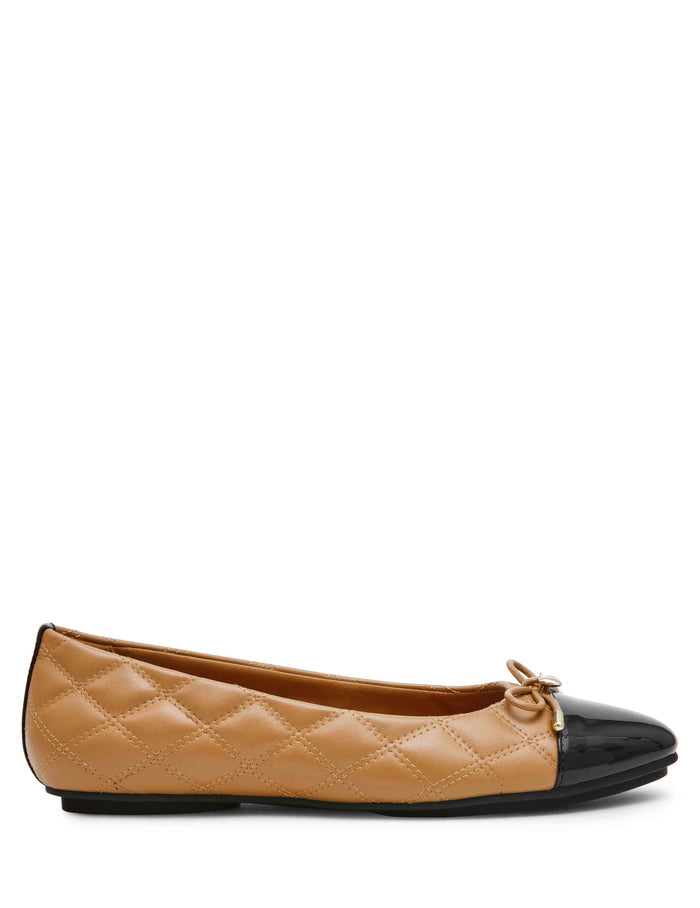 Tan quilted leather ballet flat with black patent cap toe, bow detail, and gold charm accent