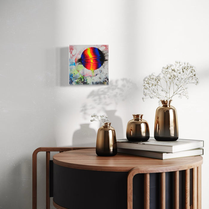 The artwork 'Thought I Saw Something' by Millie Benson features a vibrant rainbow-colored circular orb emerging from a misty white background. Created with gouache, spray paint, and conte crayon on wood, the piece combines abstract elements with sharp color contrast. The central sphere radiates with bands of red, orange, yellow, green, blue, and violet against textured white surroundings.
